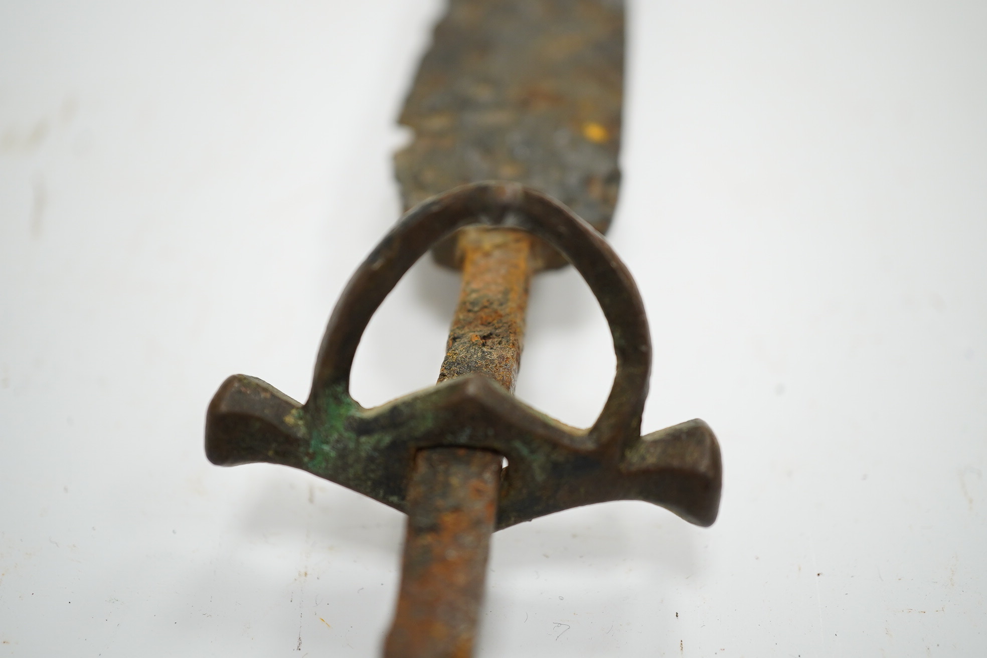 A 15th or 16th century dagger in excavated condition, broad tapered single edge blade, bronze crosspiece with side ring and fluted pommel cap, grip now missing. Condition - poor